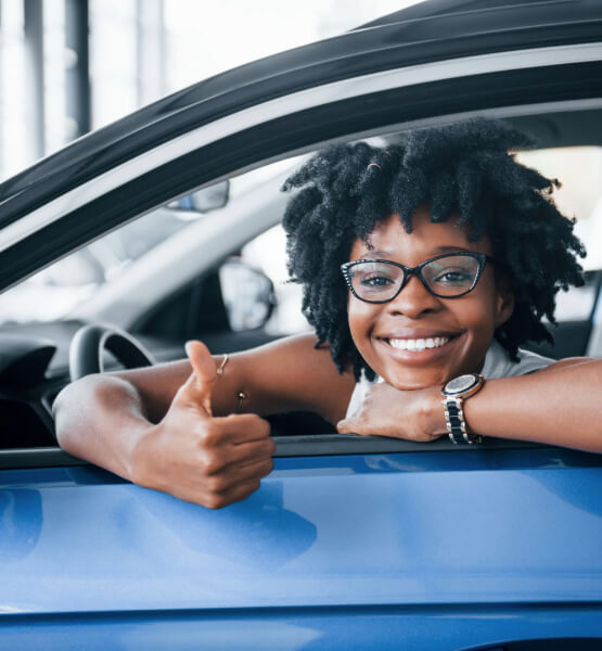 Lady thumbs up in new car.