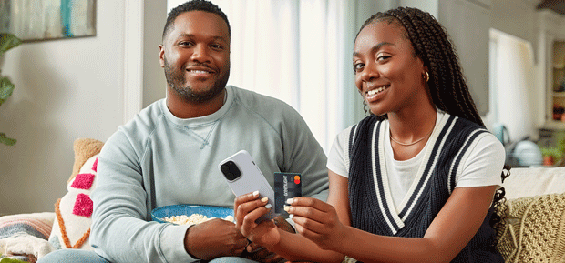 Couple on their phone and holding a Greenlight card