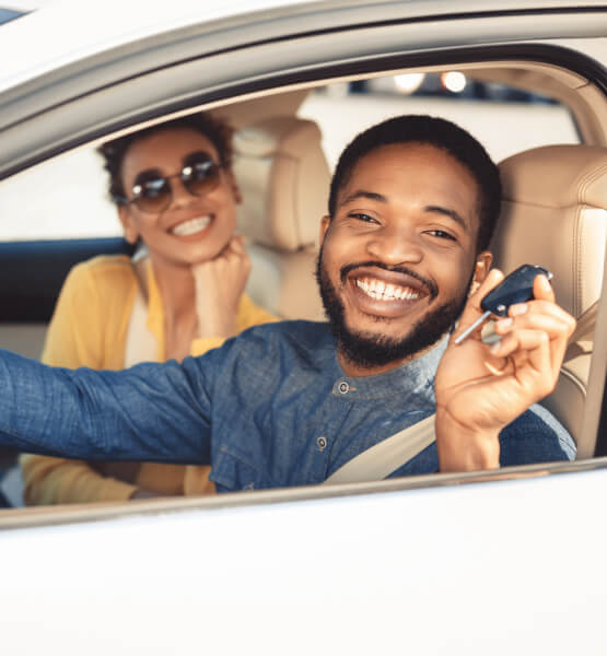 Couple in new car holding key.