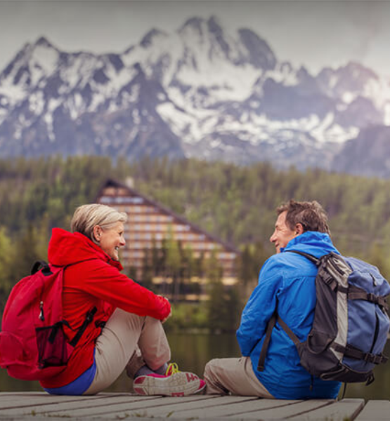 An elderly couple sitting together in front of a mountain view.