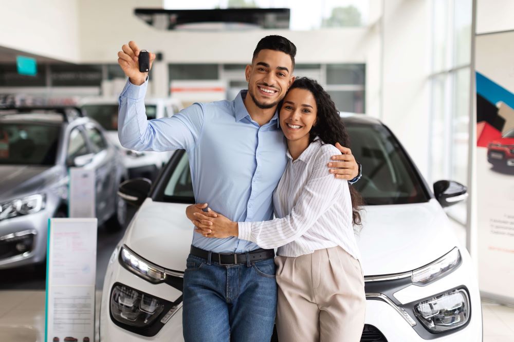 Couple holding keys to new car.