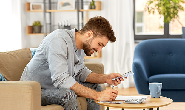 Man calculating expenses and writing them down. 