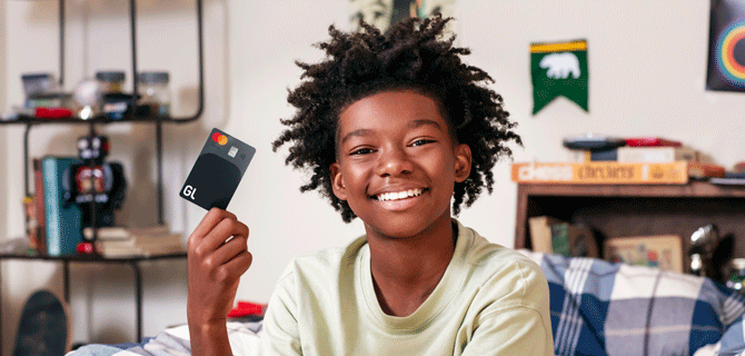 Child holding a Greenlight debit card.