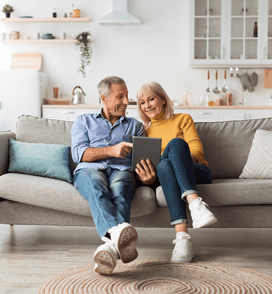 couple looking at ipad sitting on couch.