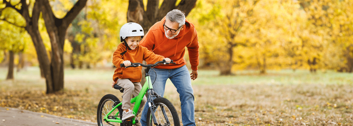 Grandpa teaching grandchild how to ride a bike.